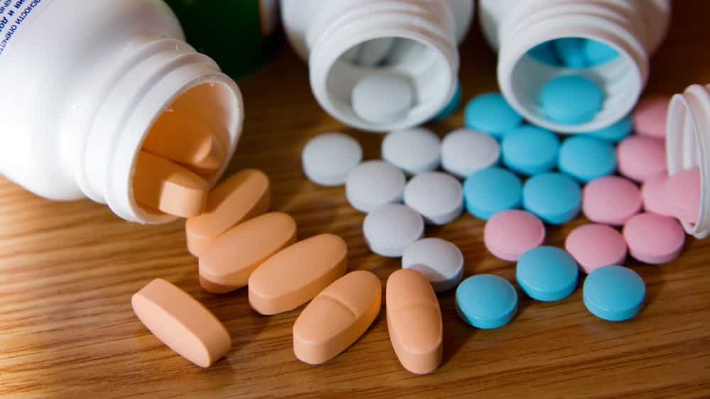 close em frascos de vitaminas abertos, com pílulas sobre a mesa. Suplementos nutricionais para câncer são desnecessários