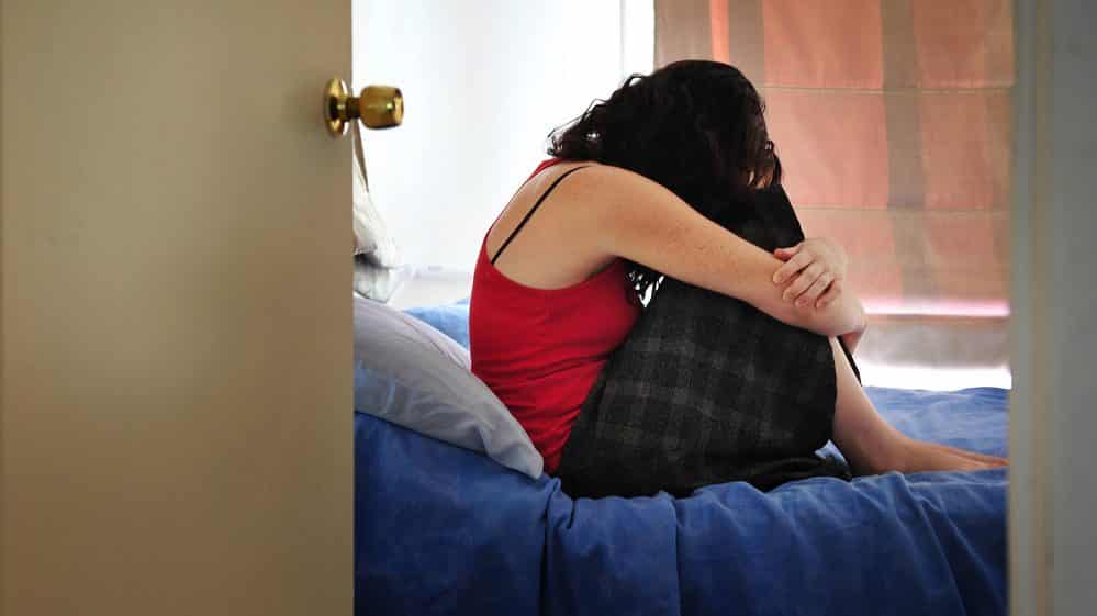Mulher deprimida, encolhida em cima da cama. Estupro deixa sequelas físicas e psicológicas
