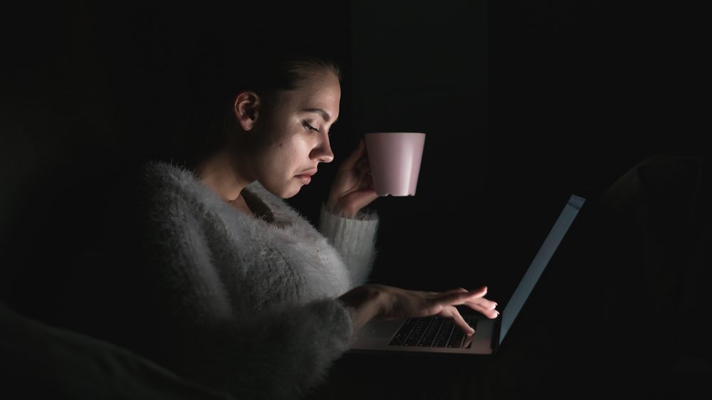 mulher acessa computador na cama, à noite. ritmo circadiano é influenciado por vários fatores