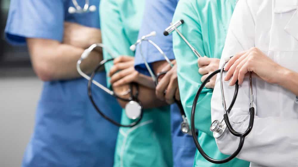 médicos enfileirados segurando estetoscópio