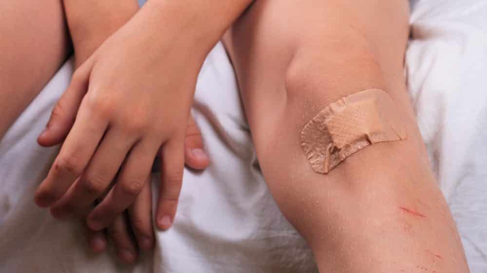 menino com joelho ralado com band-aid