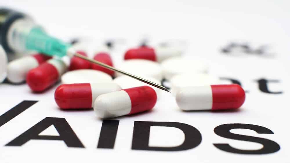 comprimidos sobre cartaz escrito 'aids'. Brasil corre o risco de ver a volta do HIV