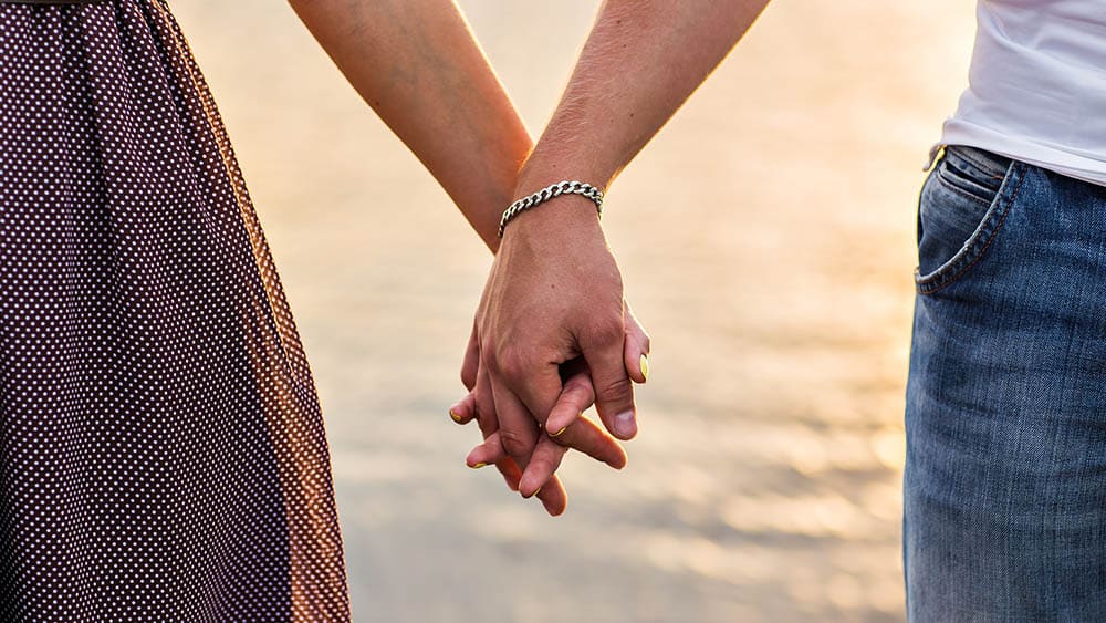 Close em mãos dadas de um homem e uma mulher. Comportamento sexual e ambiente estão relacionados