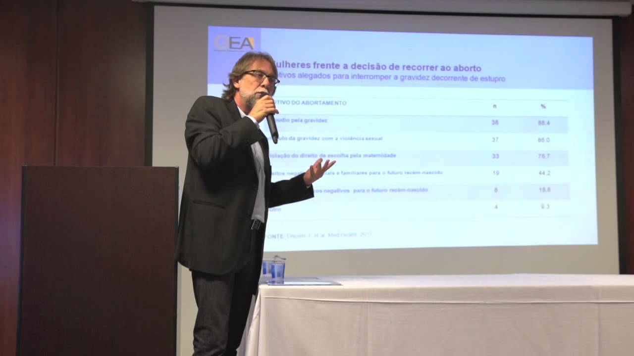 O ginecologista Jefferson Drezett em frente a u telão durante palestra sobre aborto legal.