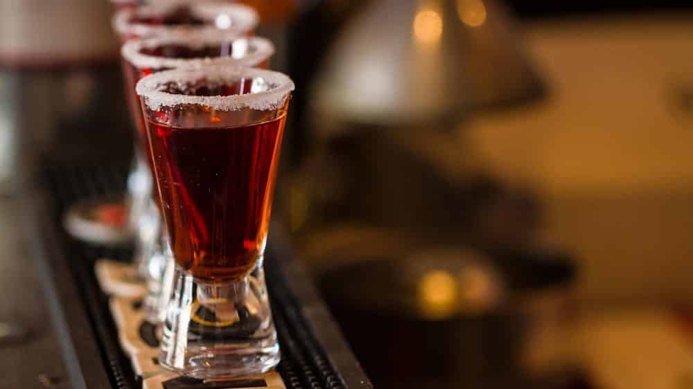 Abuso de álcool e demência | Artigo imagem de copos pequenos cheios de bebida alcoólica. Álcool e demência podem estar relacionados