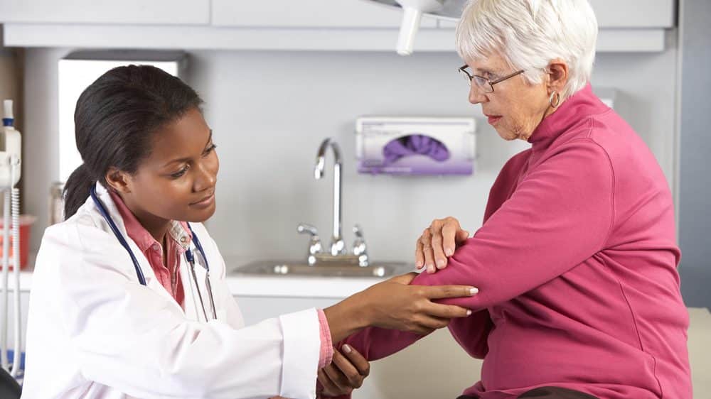 médica examina braço de idosa durante consulta médica