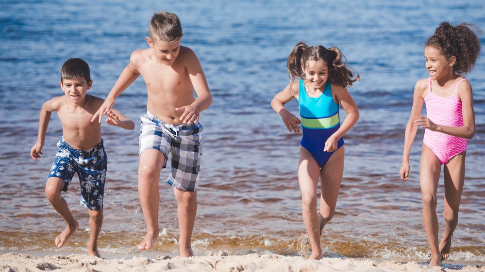 Crianças: só protetor solar não basta para protegê-las da insolação Crianças brincando na beira do mar, expostas ao sol.