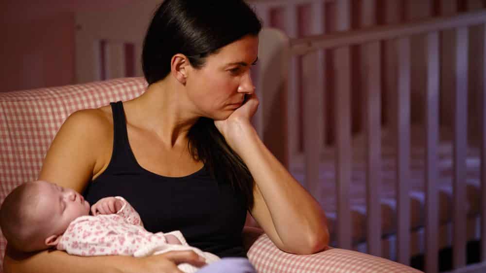 mãe sofrendo de depressão perinatal segura bebê dormindo no colo