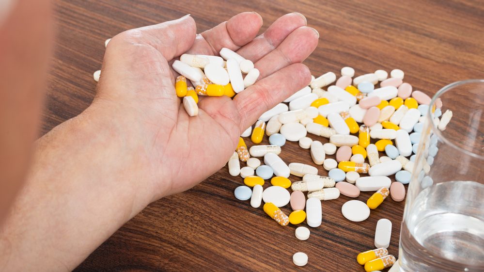 close de mão segurando vários comprimidos, indicando uso excessivo de medicamentos