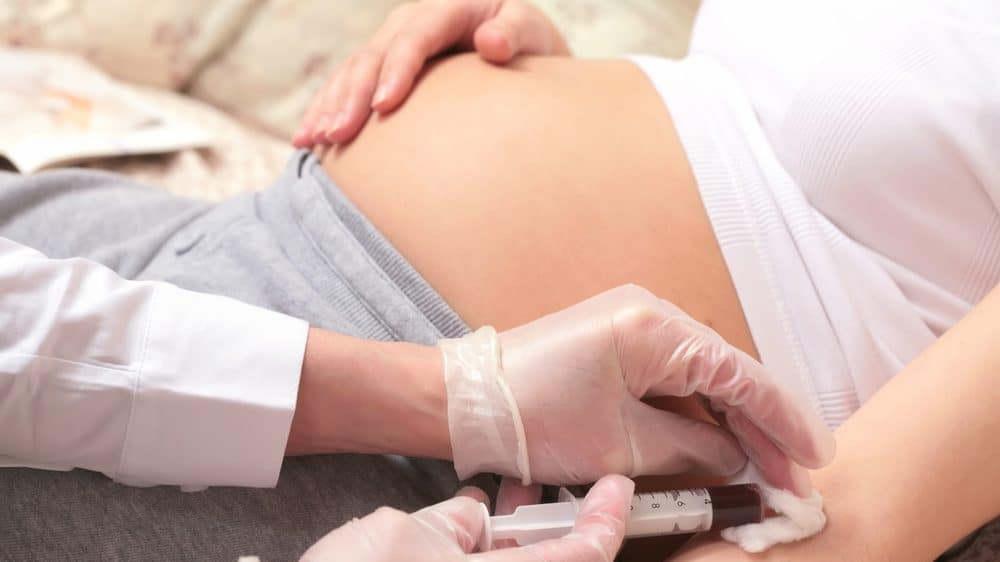 Entenda o que significa IgG positivo para citomegalovírus em grávidas mãos de médico com seringa, coletando sangue de grávida. IgG para citomegalovírus em grávidas não é motivo para alarde