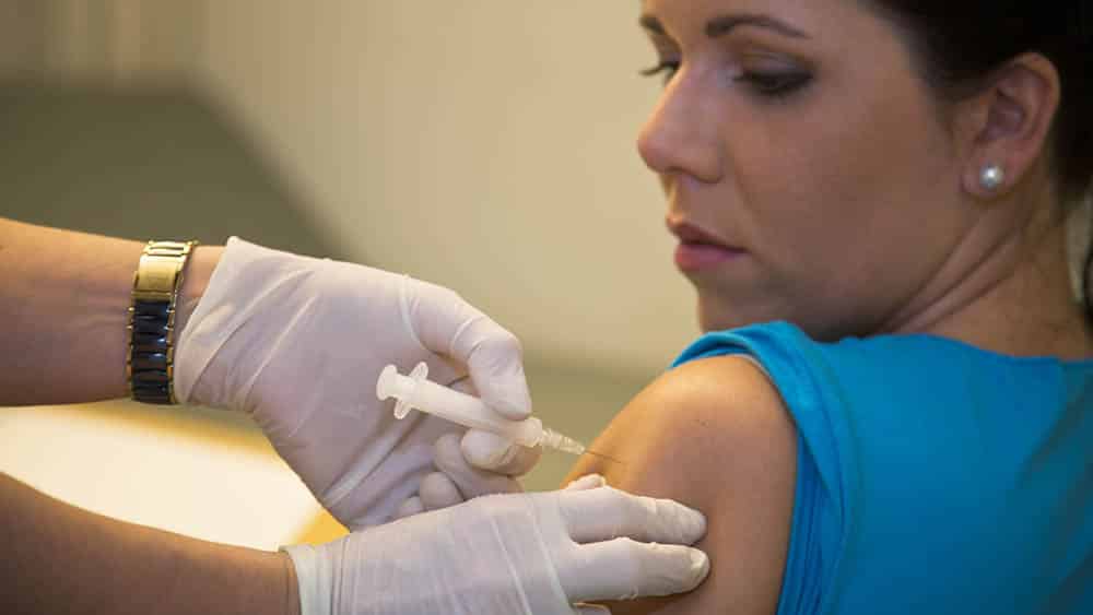 Mulher jovem recebendo vacina no braço.