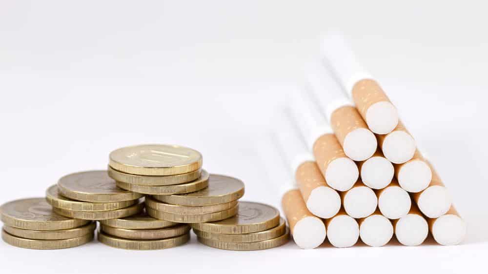 moedas e pilha de cigarros. reduzir impostos sobre o cigarro vai contra recomendação da OMS