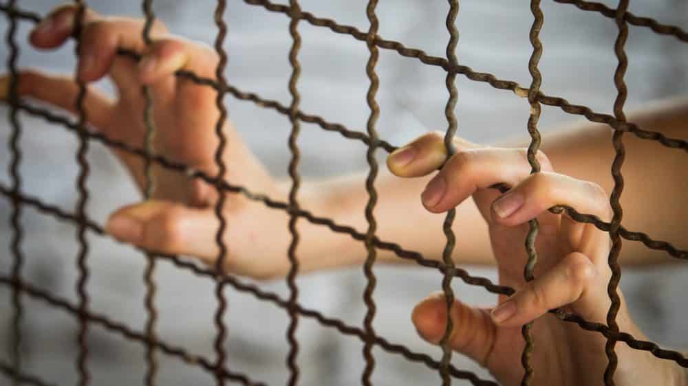 Filhos deste solo | Artigo mão de mulher presa apoiada na grade. Mulheres presas em geral são abandonadas pela família