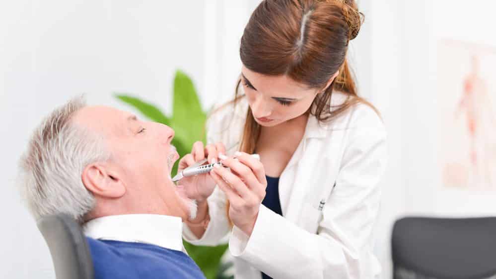 médica examina a cavidade oral de paciente. câncer de garganta atinge mais homens