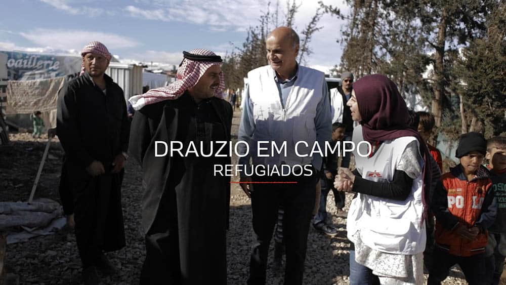 Drauzio caminhando com guias entre tendas de refugiados sírios no Líbano.