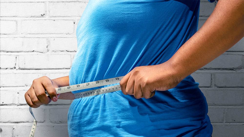 Homem obeso de perfil medindo circunferência abdominal.