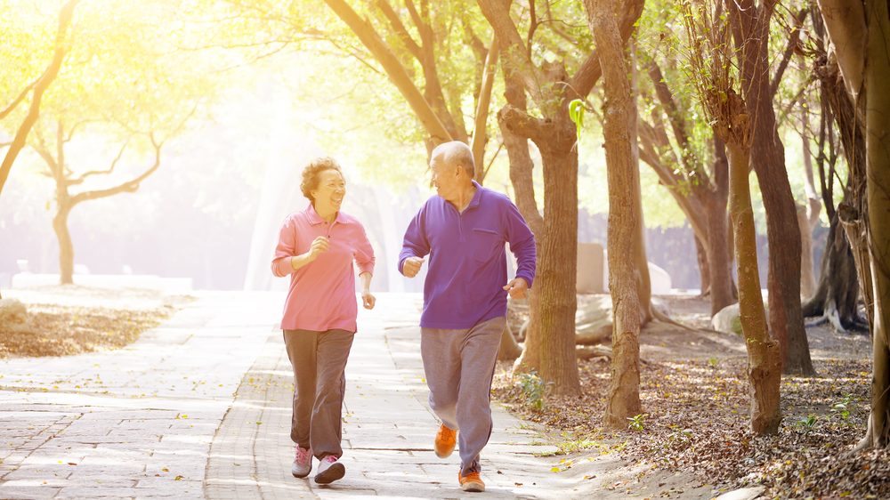 casal de idosos praticando corrida em parque. exercícios físicos regulares auxiliam na prevenção do Alzheimer