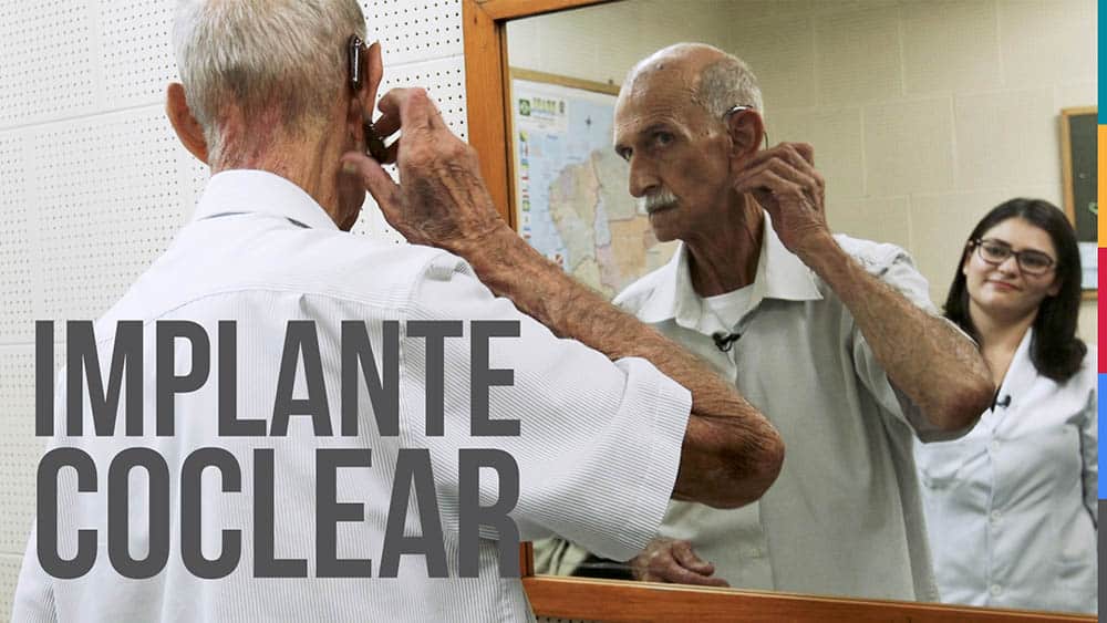 Paciente colocando aparelho de implante coclear em frente ao espelho.