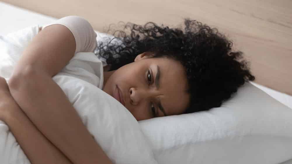 Mulher com ansiedade deitada na cama.
