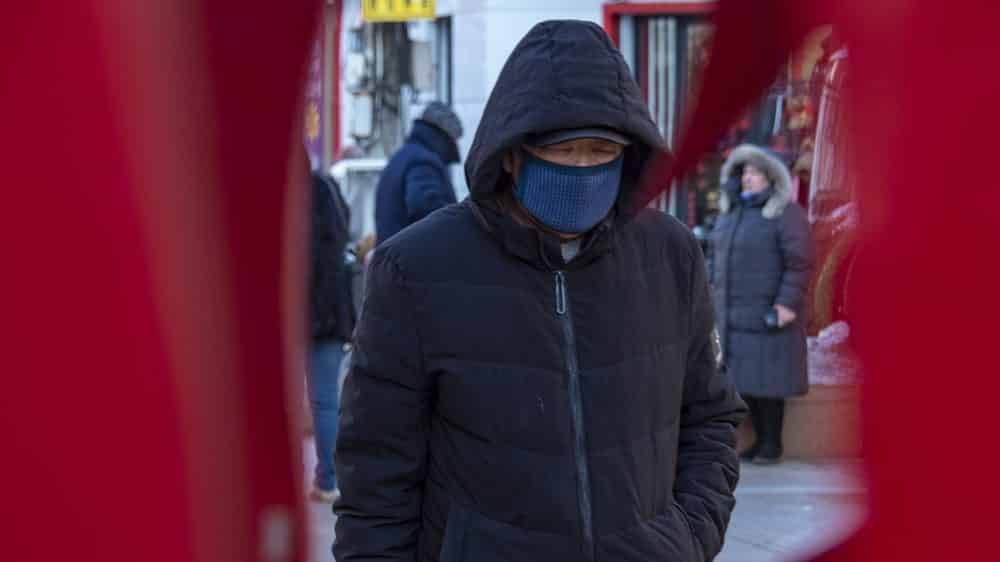 homem usa máscara para se proteger do novo coronavírus em rua da China