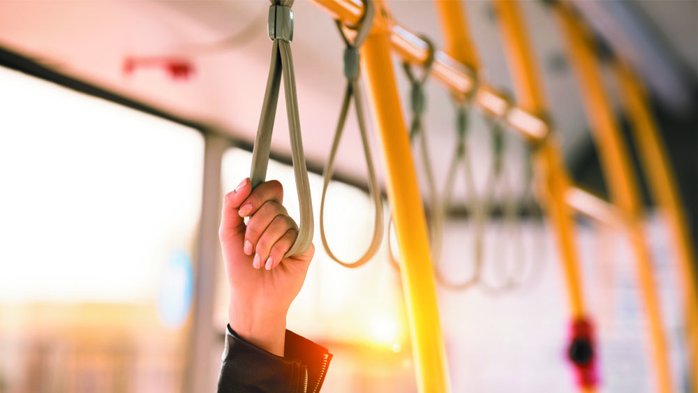 Mão de mulher segurando em apoio do transporte público. Higienizar as mãos com álcool em gel é essencial para se prevenir do novo coronavírus.