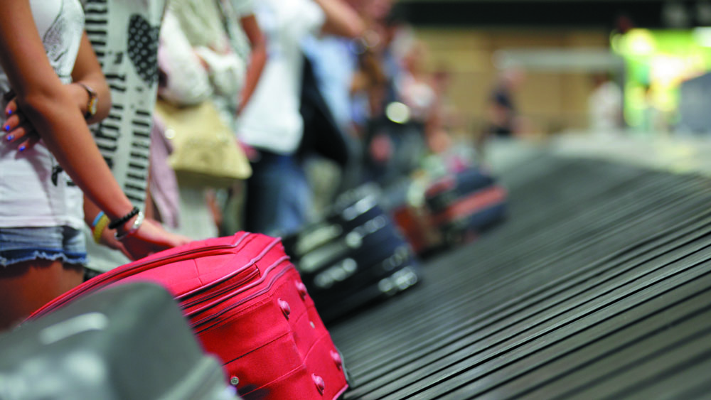Pessoas chegando de viagem internacional aguardando sua bagagem. Elas devem ficar atentas aos sintomas que podem indicar infecção pelo novo coronavírus