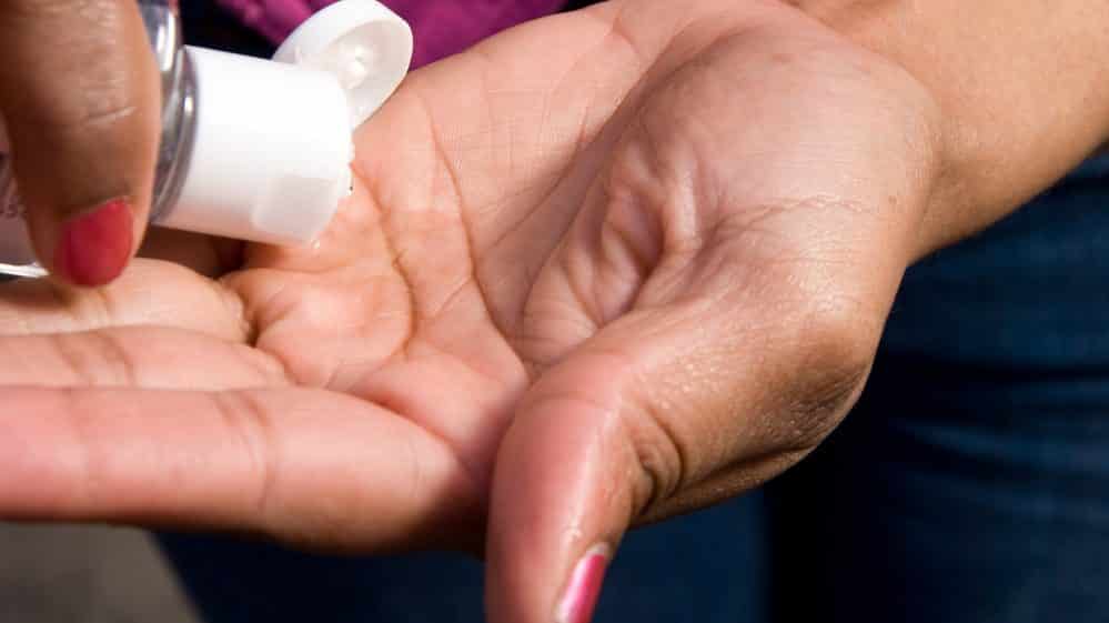 Close em mãos da mulher passando álcool em gel. Veja as medidas de higiene para prevenir o coronavírus
