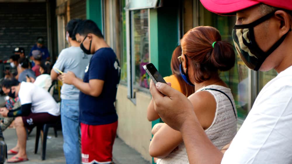 pessoas usando máscara em frente a um supermercado