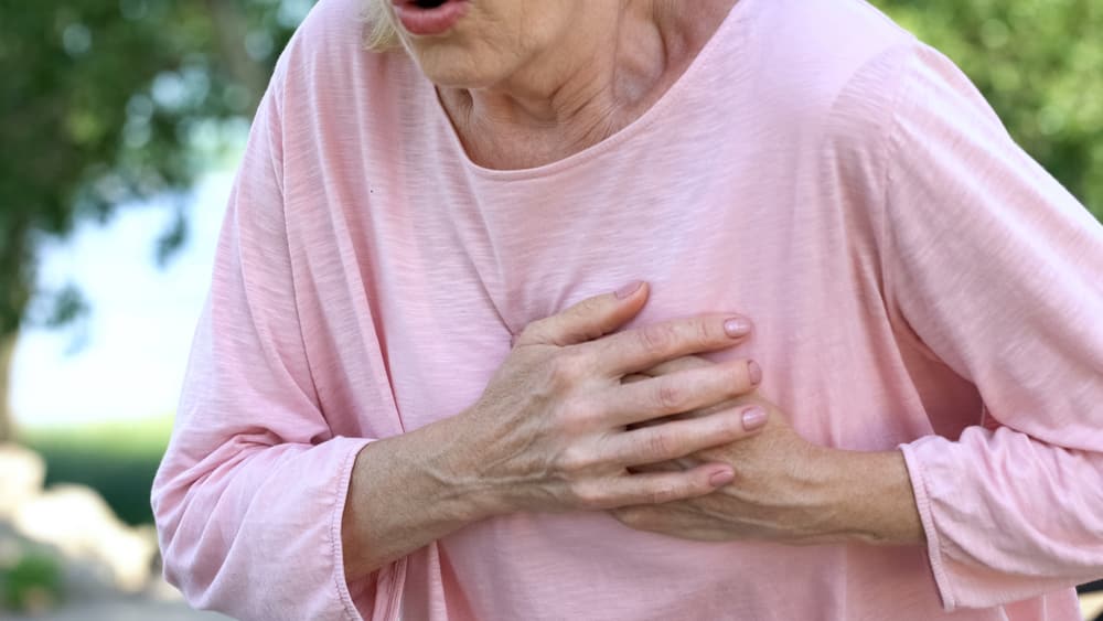 mulher idosa com mão no peito. infarto nas mulheres tem aumentado