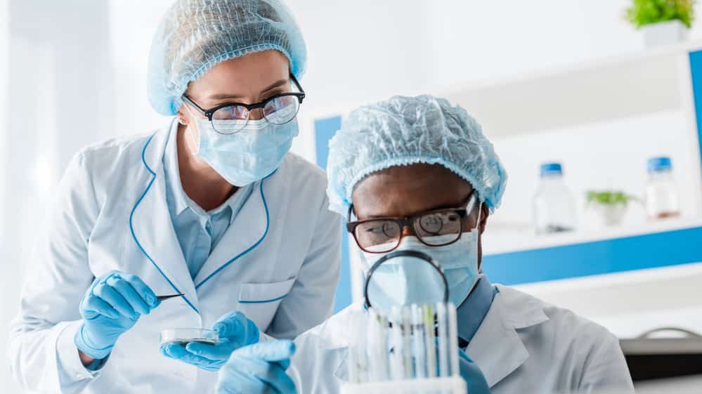 pesquisadores paramentados observam lâmina em laboratório. pesquisa identificou a presença do novo coronavírus no sêmen de pacientes,