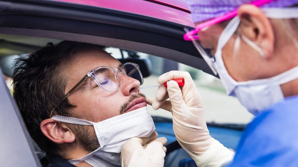 enfermeira colhe secreção nasal de paciente em carro para realizar exame. Testes para o novo coronavírus estão disponíveis em laboratórios