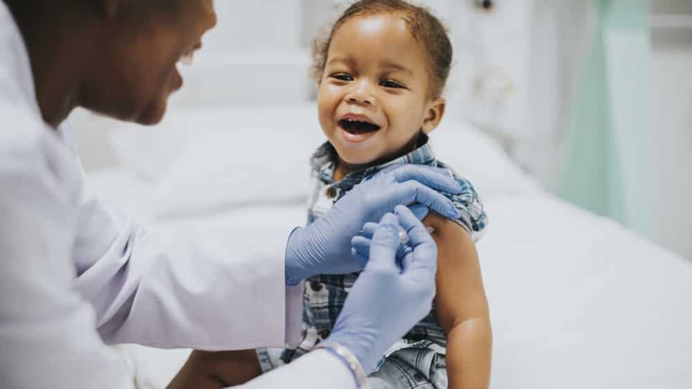 menina pequena toma injeção no braço dada por médica. vacina contra a covil-19 é aguardada