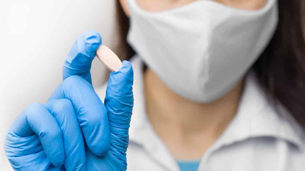 cientista de luva e máscara segura comprimido de hidroxicloroquina.