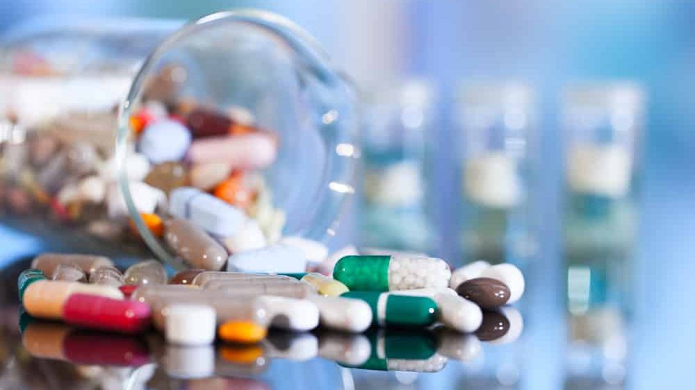 frasco derrubado com vários comprimidos de novos antibióticos caídos