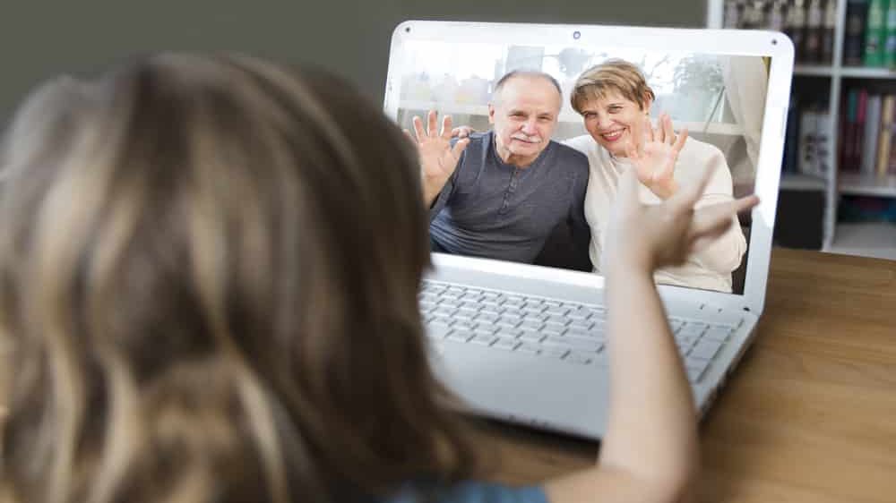 criança de costas acena para avós na tela do computador. Festas de fim de ano devem ser suspensas por causa da covid-19