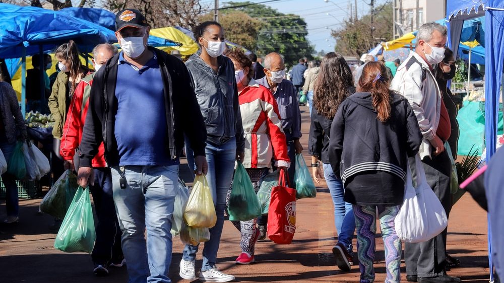 pessoas aglomeradas em feira no Brasil. Com mais variantes do coronavírus, aumentam os casos da doença