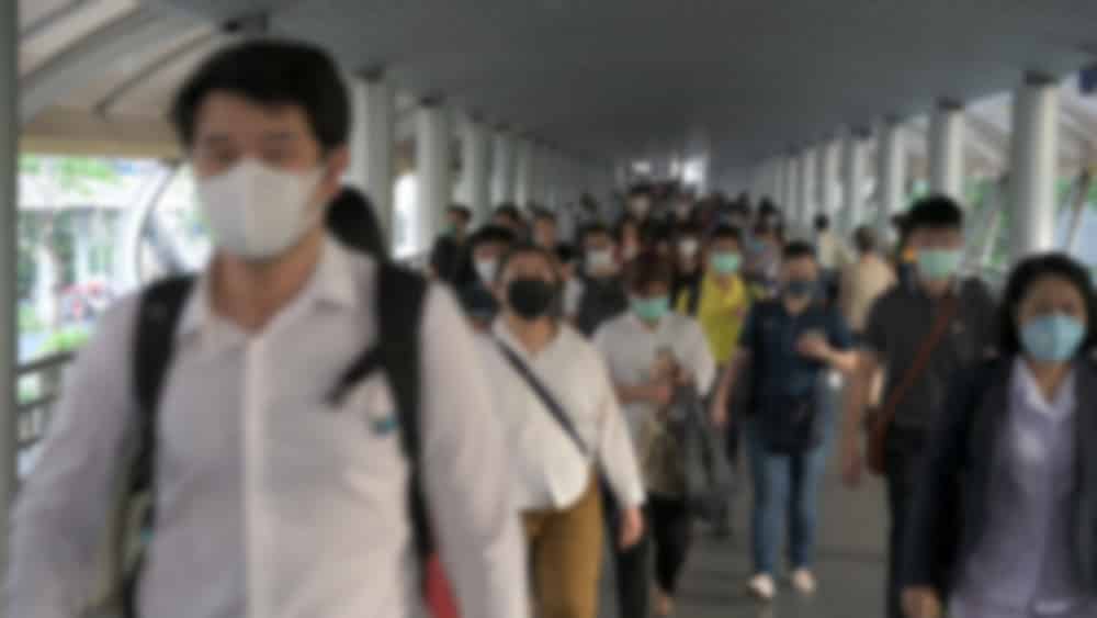 imagem desfocada de pessoas com máscara em lugar cheio durante a pandemia do coronavírus